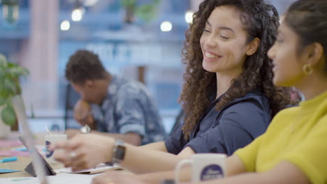 Mujer-Sonriente-Que-Trabaja-Con-Un-Colega-En-La-Oficina-Abierta