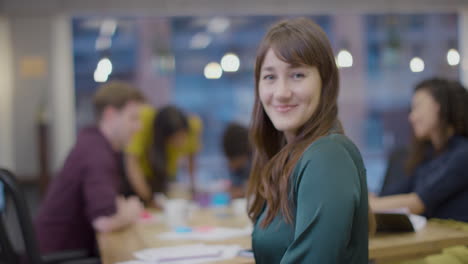 Portrait-of-a-businesswoman-in-office-with-colleagues-working-in-background-