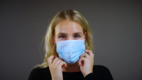 Young-Blonde-Woman-Puts-On-Face-Mask