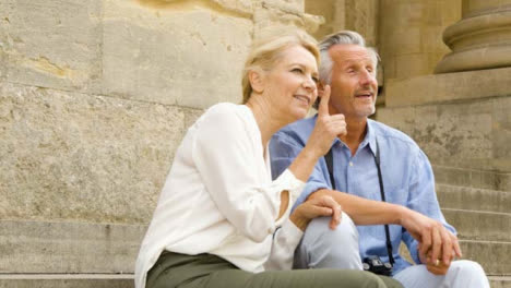Medium-Shot-of-Middle-Aged-Tourist-Couple-On-Steps-Talking