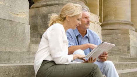 Medium-Shot-of-Middle-Aged-Tourist-Couple-Reading-Map-On-Steps