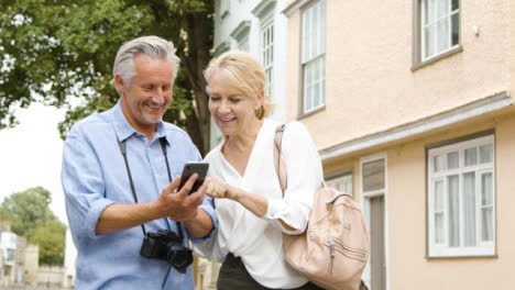 Low-Angle-Shot-Eines-Paares-Mittleren-Alters,-Das-Karte-Auf-Dem-Telefon-Liest