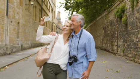 Medium-Tracking-Shot-of-Middle-Aged-Tourist-Couple-Taking-Selfie-