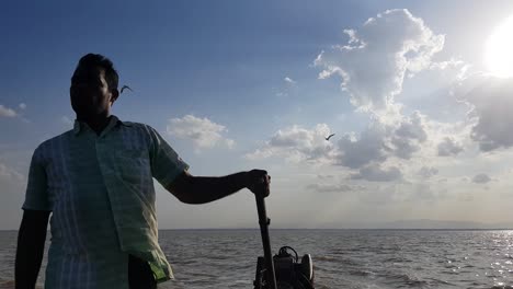 Irukkam-Island-Andhra-Pradesh--India--July-22-2019-Wide-angle-view-of-a-boat-man-driving-a-motorboat-with-dramatic-sky-and-clouds-in-the-background