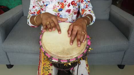 Medium-wide-looking-down-isolated-shot-of-a-woman-playing-djembe-drum