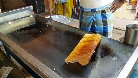 Un-Hombre-Haciendo-Dosa-En-Una-Enorme-Placa-De-Piedra