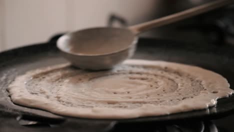 Closeup-of-making-steaming-hot-Dosa-on-a-cast-iron-pan.-Dosa-is-the-Indian-version-of-pancake-made-with-rice-flour-dough