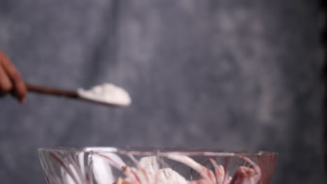 Dramatic-slow-motion-closeup-of-multipurpose-flour-thrown-from-a-spatula-into-a-glass-bowl