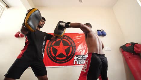 Bengaluru-Karnataka--India--February-13-2020-Looking-up-shot-of-a-professional-mixed-martial-arts-fighter-doing-round-house-spinning-back-kick-and-another-fighter-holding-the-pads-in-slow-motion