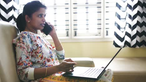 Closeup-of-an-Indian-business-woman-working-from-home-sitting-on-a-sofa-and-talking-on-teléfono-due-to-the-covid19-coronavirus-lockdown.