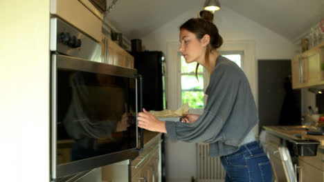 Young-Woman-Placing-Baking-Tin-In-Oven