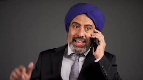 Annoyed-Middle-Aged-Businessman-In-Turban-Shouting-On-Phone