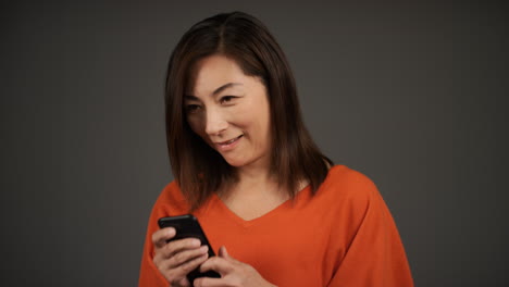 Frau-Mittleren-Alters,-Die-Auf-Ihrem-Telefonporträt-Lächelt-Und-SMS-Schreibt