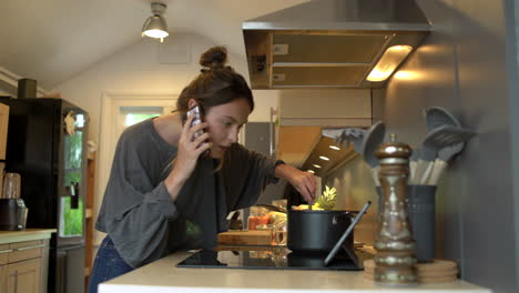 Low-Angle-Shot-of-Young-Woman-On-Phone-Whilst-Cooking