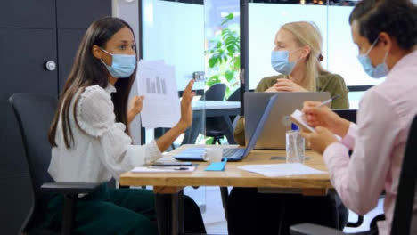 Three-Young-Business-Colleagues-In-Face-Masks-Having-a-Discussion