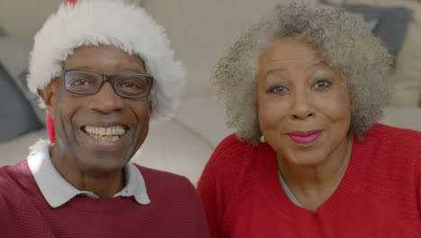Older-Couple-Waving-Hello-and-Listening-During-Christmas-Video-Call