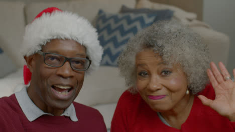 Older-Couple-Waving-Hello-and-Listening-Intently-During-Christmas-Video-Call