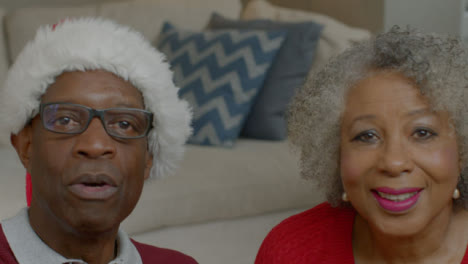 älteres-Ehepaar-Spricht-Und-Winkt-Während-Des-Weihnachtsvideoanrufs-Zum-Abschied