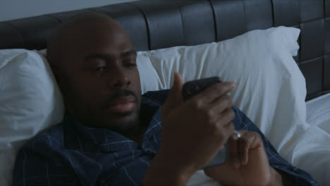 Middle-Aged-Man-Laying-In-Bed-Looking-at-His-Smartphone-