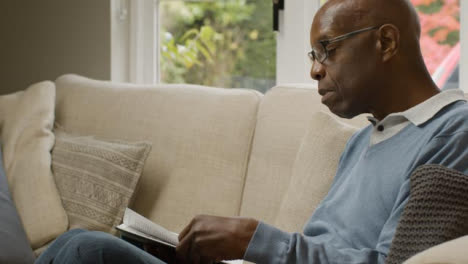 Middle-Aged-Man-Sitting-On-Sofa-Reading-a-Book