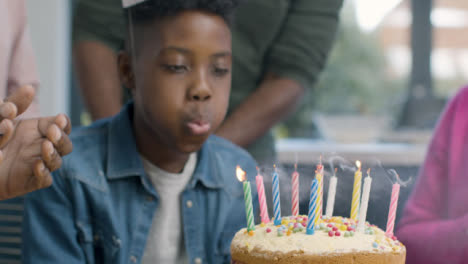 Kleiner-Junge-Bläst-Kerze-Auf-Kuchen-Aus,-Nachdem-Familie-Alles-Gute-Zum-Geburtstag-Gesungen-Hat
