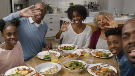 Family-Talking-Directly-to-Camera-During-Video-Call-at-Dinner