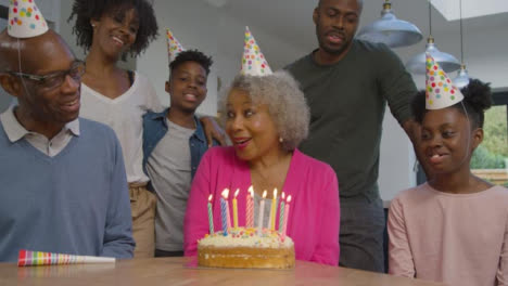 Familie-Singt-Alles-Gute-Zum-Geburtstag-Für-ältere-Verwandte,-Bevor-Sie-Kuchenkerzen-Ausbläst