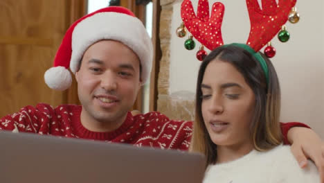 Close-Up-of-Joyful-Couple-Talking-Into-Laptop-During-a-Christmas-Video-Call