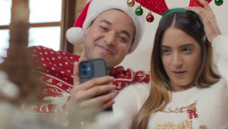 Pull-Focus-Shot-of-Couple-Talking-Into-Phone-During-Christmas-Video-Call