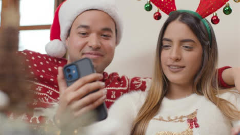 Pull-Focus-Shot-of-Couple-Talking-Into-Phone-During-a-Christmas-Video-Call