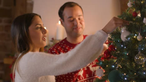 Mittlere-Aufnahme-Eines-Jungen-Paares,-Das-Zusammen-Den-Weihnachtsbaum-Schmückt