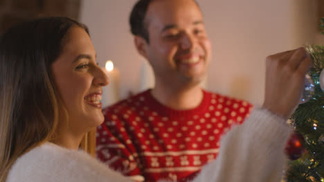 Close-Up-Shot-of-Young-Couple-Decorating-a-Christmas-Tree-Together