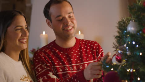 Mittlere-Aufnahme-Eines-Jungen-Paares,-Das-Zusammen-Einen-Weihnachtsbaum-Schmückt