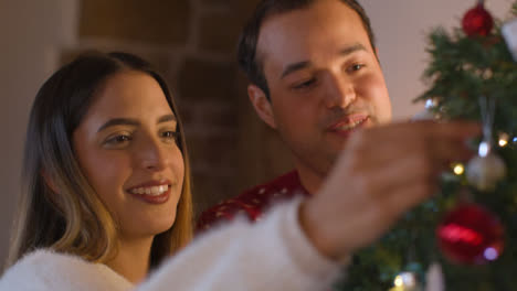 Close-Up-Shot-of-Joyful-Young-Couple-Decorating-Christmas-Tree-Together