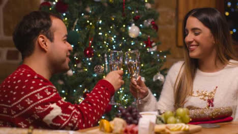 Mittlere-Aufnahme-Eines-Paares,-Das-Seine-Champagnergläser-Zusammenbringt,-Bevor-Es-Weihnachtscracker-Zieht