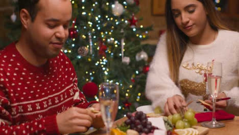 Tilting-Shot-of-Young-Couple-Eat-a-Table-Spread-Together-During-Christmas-