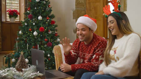 Wide-Shot-of-Young-Couple-Talking-to-Laptop-Camera-During-Christmas-Video-Call