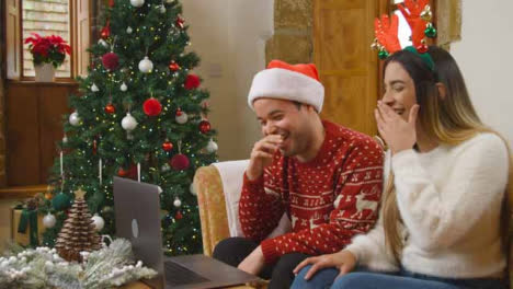 Wide-Shot-of-Young-Couple-Laughing-and-Talking-to-Laptop-Camera-During-Christmas-Video-Call-