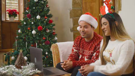 Plano-Amplio-De-Pareja-Joven-Hablando-Con-Una-Cámara-Portátil-Durante-La-Videollamada-De-Navidad