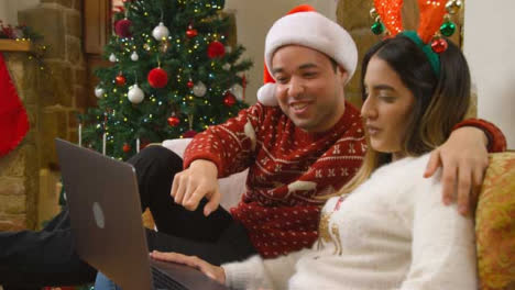 Medium-Shot-of-Young-Couple-Talking-to-Laptop-Camera-During-Christmas-Video-Call-