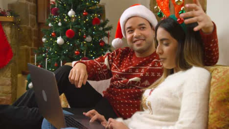 Medium-Shot-of-Young-Couple-Talking-to-Laptop-Webcam-During-a-Christmas-Video-Call-