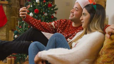 Medium-Shot-of-Young-Couple-Talking-to-Phone-Camera-During-Christmas-Video-Call