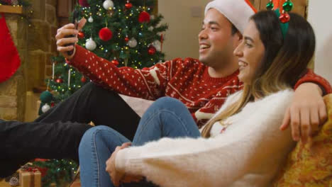 Medium-Shot-of-Young-Couple-Talking-to-a-Phone-Camera-During-Christmas-Video-Call