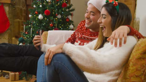 Medium-Shot-of-Young-Couple-Laughing-and-Talking-to-Phone-Camera-During-a-Christmas-Video-Call