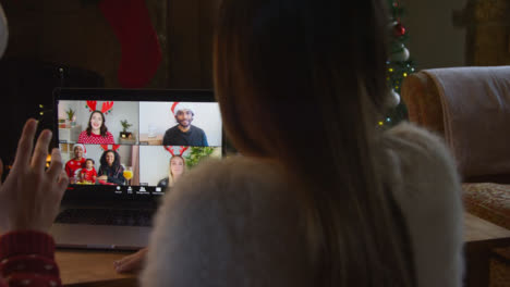 Over-the-Shoulder-Shot-of-Couple-Talking-to-Friends-On-a-Laptop-Christmas-Video-Call