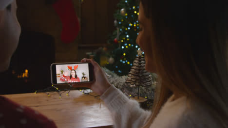 Over-the-Shoulder-Shot-of-Couple-Talking-to-Friend-Using-Laptop-Christmas-Video-Call