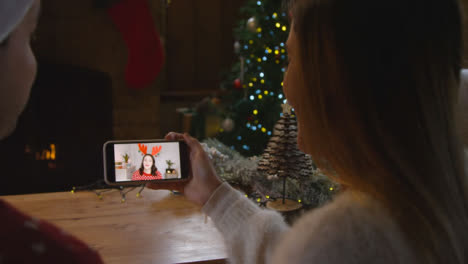 Over-the-Shoulder-Shot-of-Couple-Talking-to-Friend-Via-Phone-Christmas-Video-Call