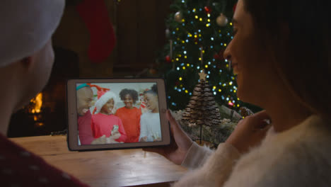 Over-the-Shoulder-Shot-of-Couple-Waving-and-Talking-to-Family-Friends-On-Christmas-Video-Call
