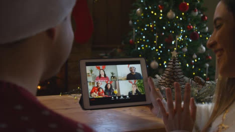 Over-the-Shoulder-Shot-of-Couple-Talking-to-Friends-On-a-Tablet-Christmas-Video-Call