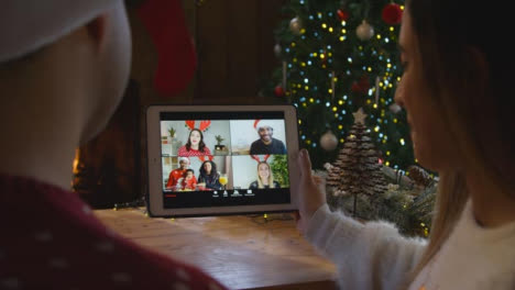 Over-the-Shoulder-Shot-of-Couple-Talking-to-Friends-On-Tablet-Christmas-Video-Call